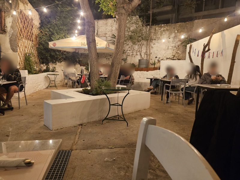 Tables in the tree shaded courtyard of Vaggelis & Alekos, Neos Kosmos, on an October evening